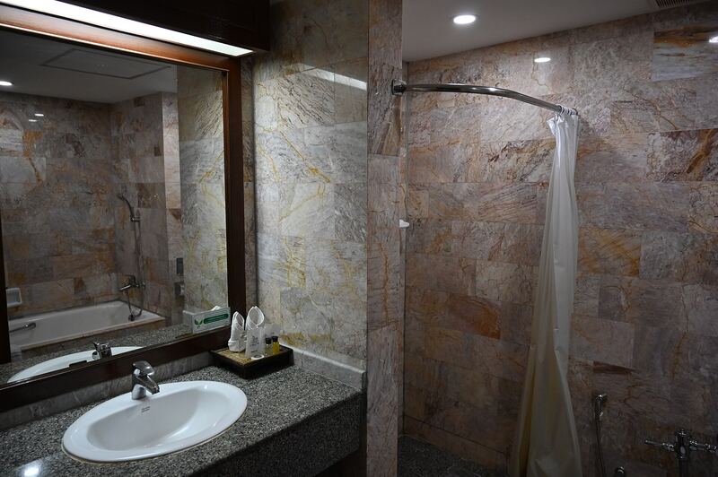 Shower room with marble-patterned walls, a stone counter with basin and a large mirror