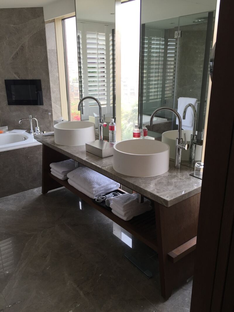 Bathroom vanity with a dark stone counter, two raised basins and towels on a shelf beneath
