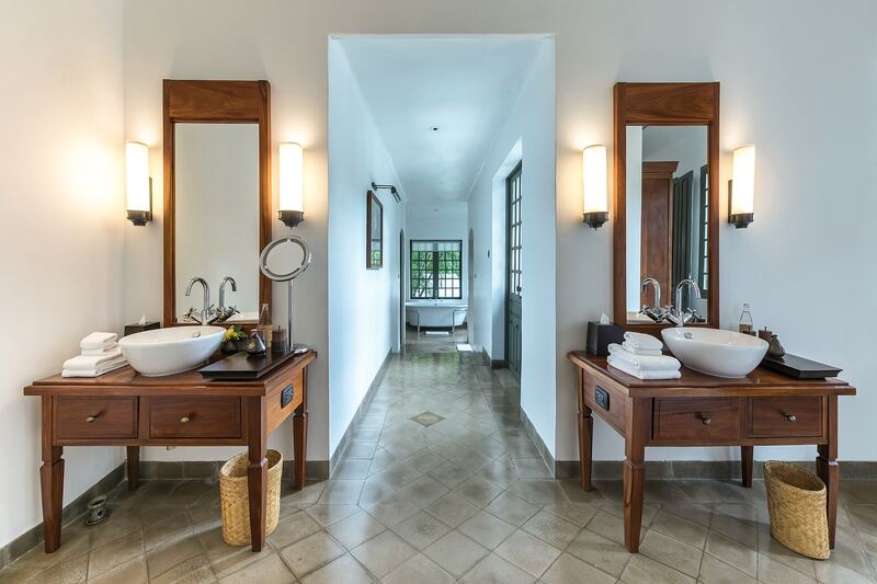 Bathroom with two wooden vanity tables, round basins and mirrors either side of a corridor