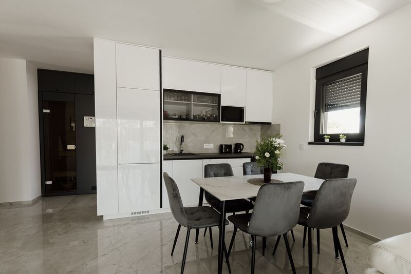 Bright apartment with a white kitchen along one wall and a dining table nearby