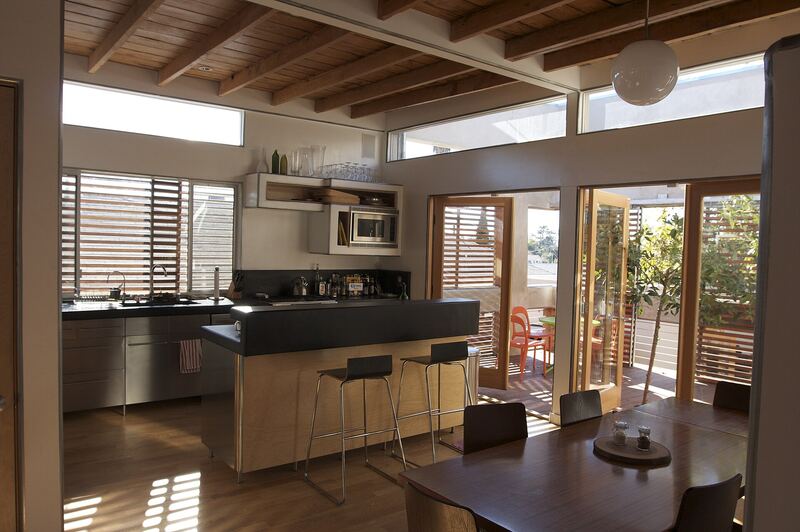 Kitchen with a timber ceiling, dark worktops and glazed doors opening to a garden