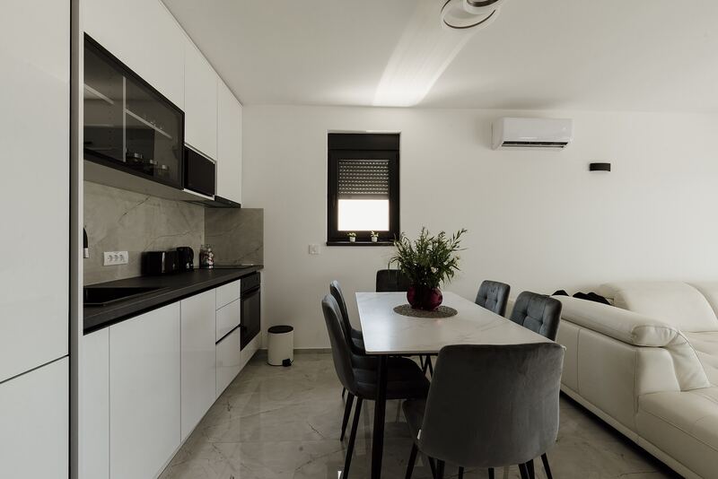 Single-wall kitchen with pale units in an open living area with a dining table