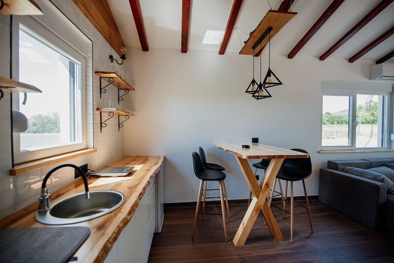Compact kitchen run with a wooden worktop, sink and open shelves near a window
