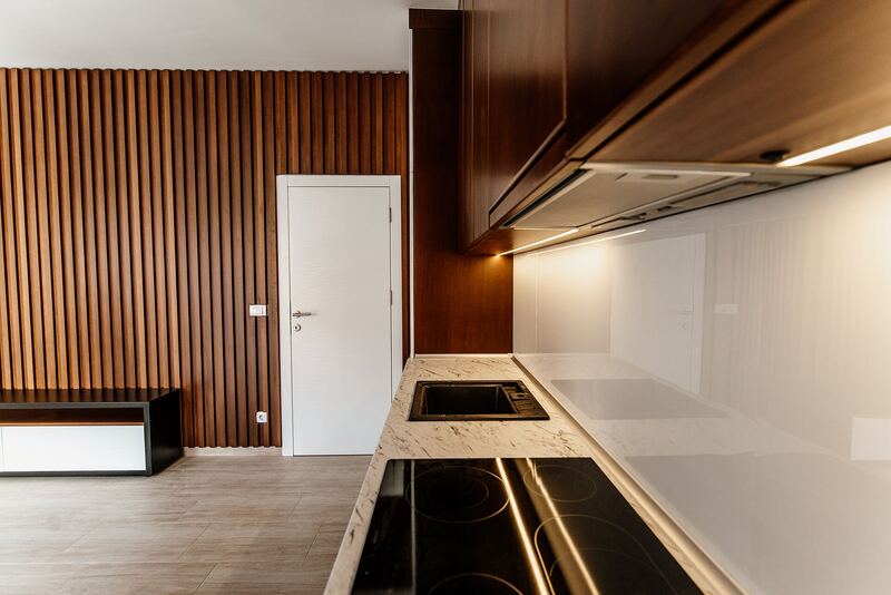 Living space with a slatted wooden wall, built-in kitchen units and a glossy island