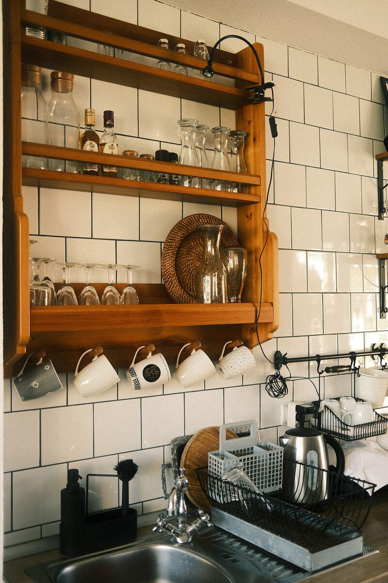 Wooden open shelving holding plates, bowls and glasses in a kitchen