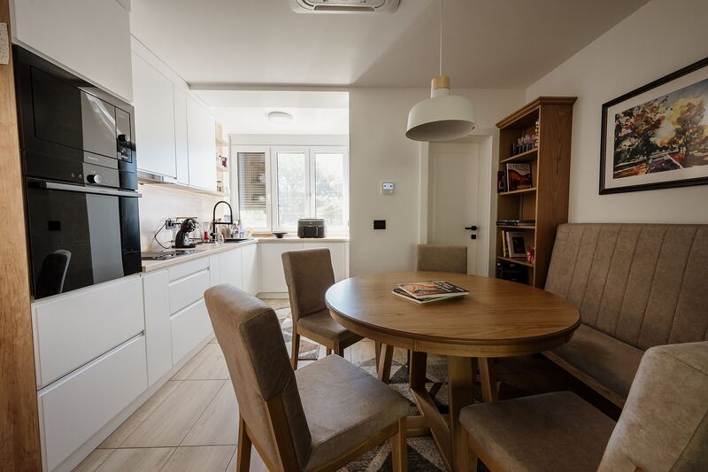 Light kitchen with wall cabinets beside a round wooden dining table and chairs